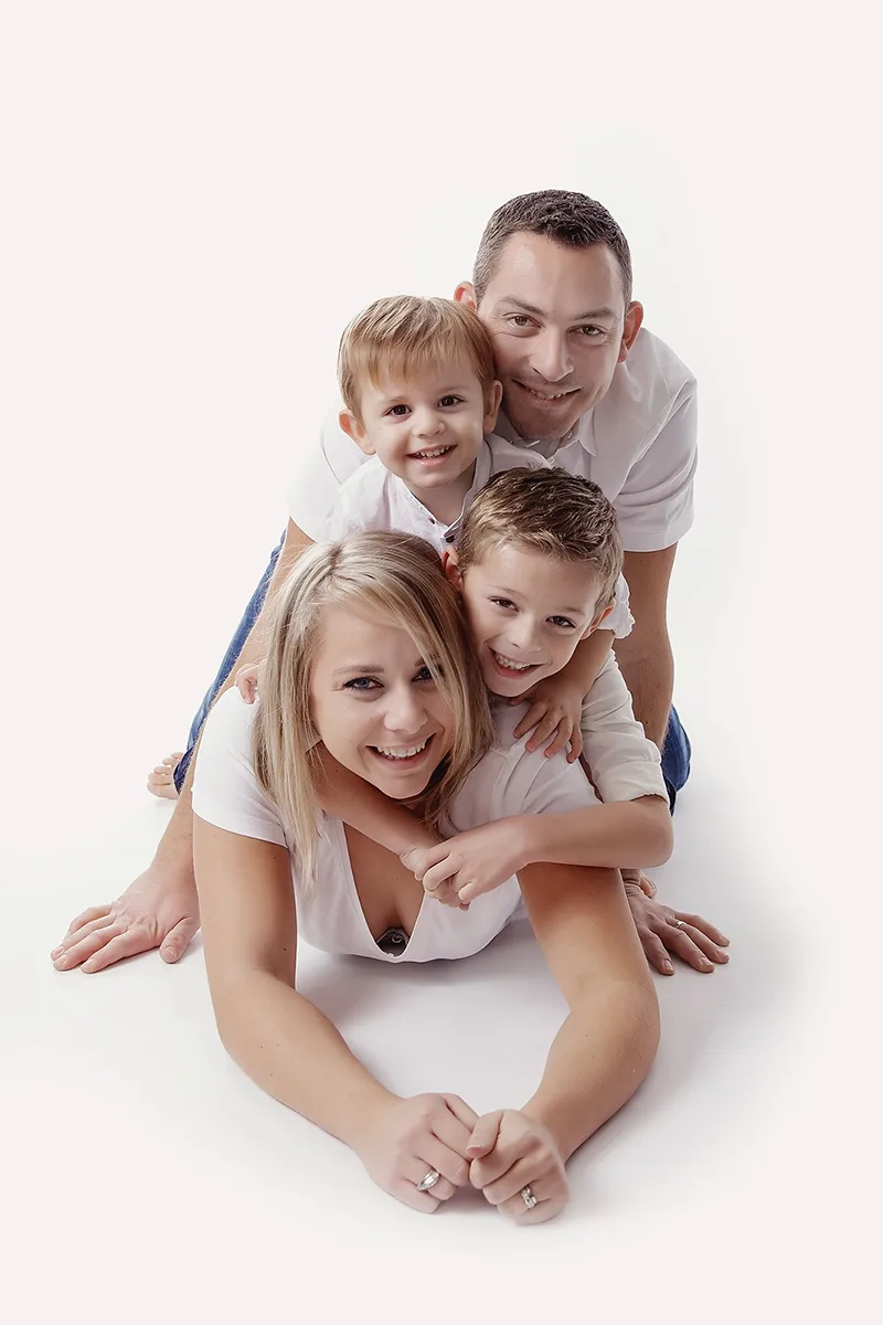 Parents avec leurs deux garçons partageant un moment complice lors d’une séance photo de famille en studio.
