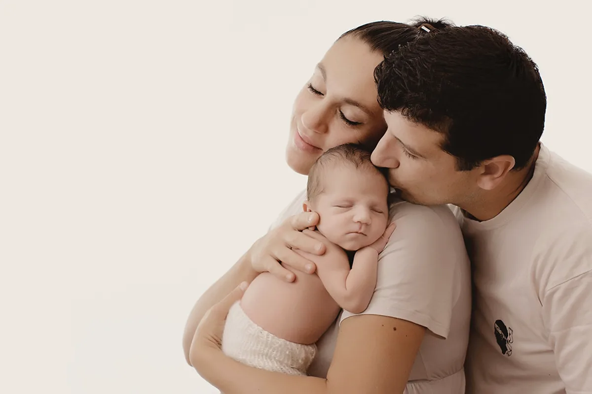 Jeunes parents entourant tendrement leur nouveau-né lors d’une séance photo naissance en studio.