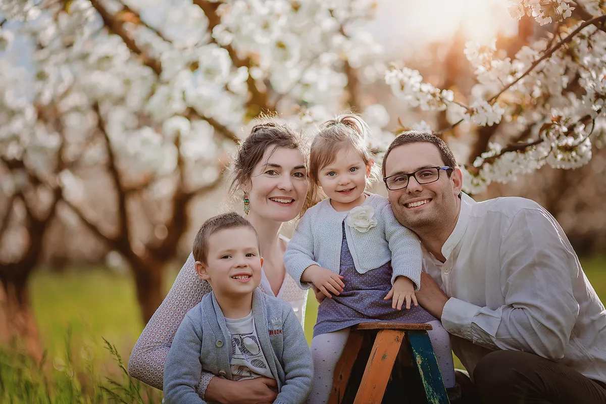 Famille avec deux enfants photographiée sous les arbres en fleurs dans le Luberon